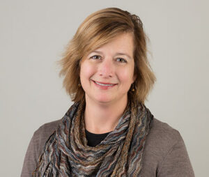 Image of Sue Rogan smiling behind a beige background