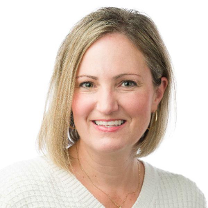 Award winner Jenni Whitely smiling in front of a white background in a white sweater